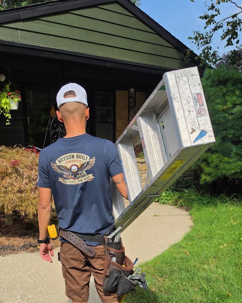 Sammy Bryson carrying an extension ladder up the driveway to a job
